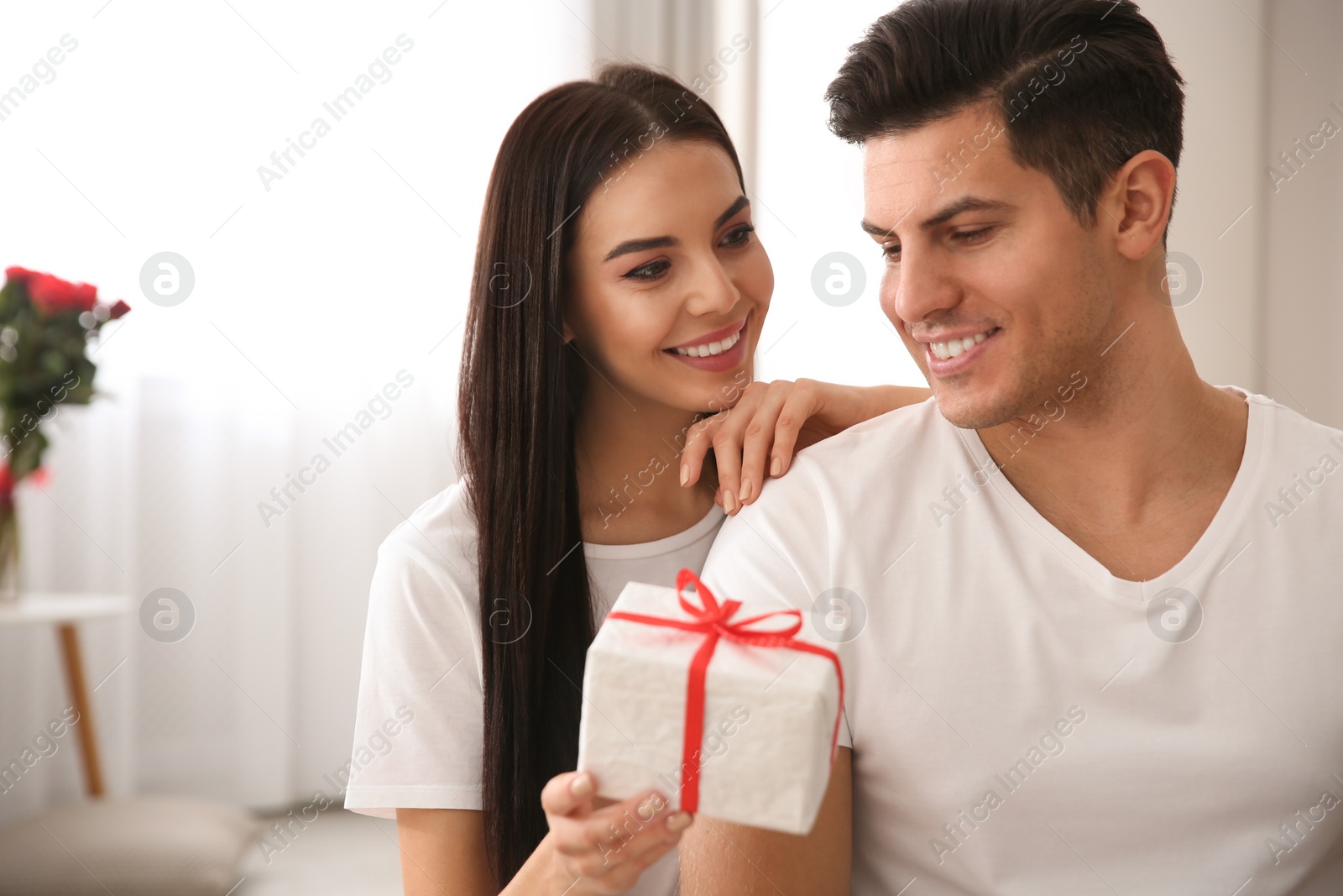 Photo of Lovely couple with gift box at home. Valentine's day celebration