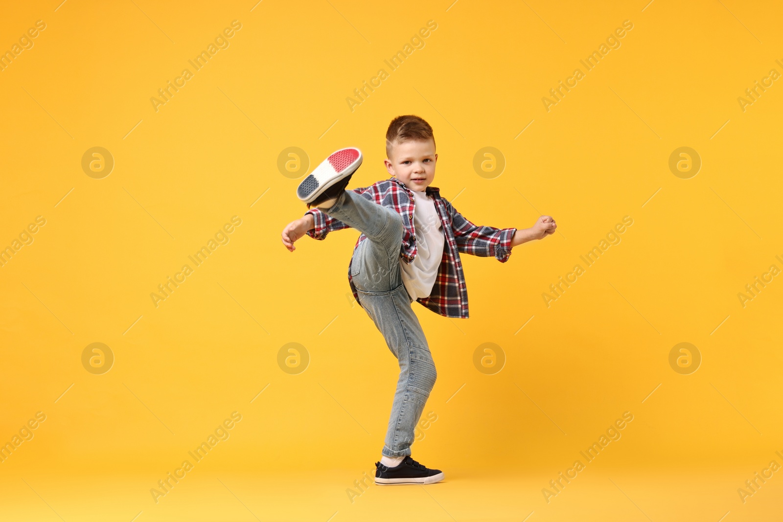 Photo of Happy little boy dancing on yellow background