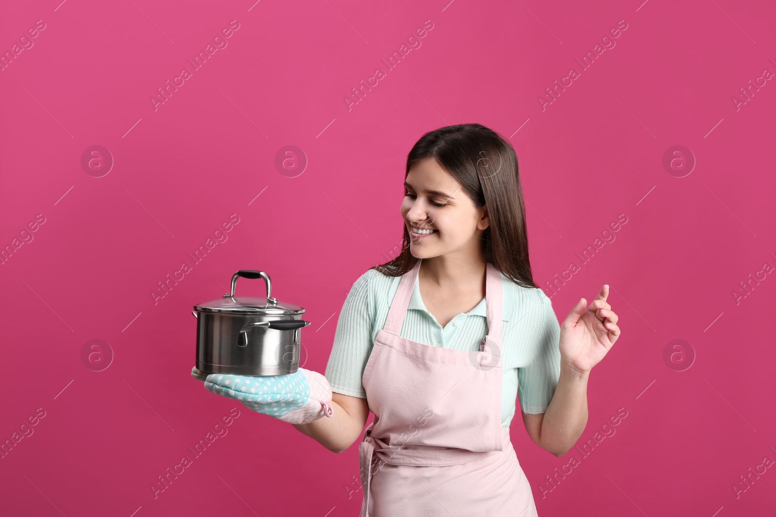 Photo of Happy young woman with cooking pot on pink background