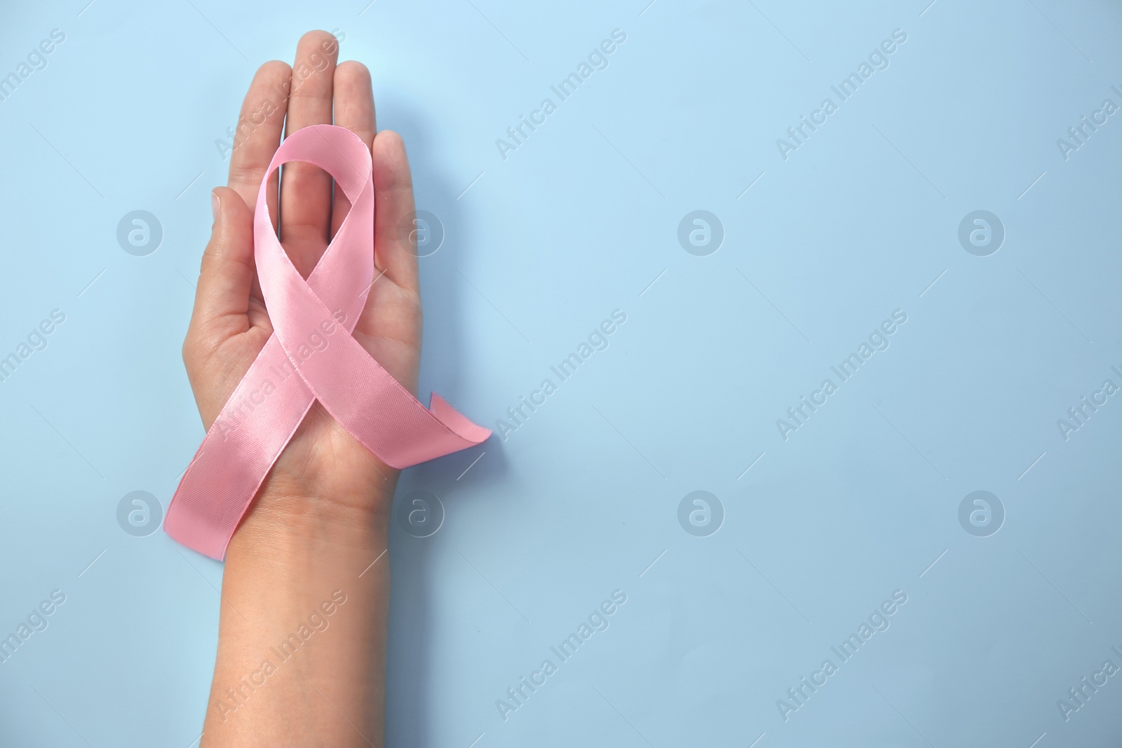 Photo of Woman holding pink ribbon on color background, top view. Gynecological cancer