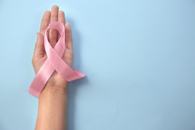 Woman holding pink ribbon on color background, top view. Gynecological cancer