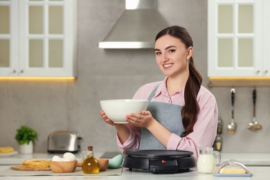 Photo of Happy woman with dough for crepes at white marble table in kitchen