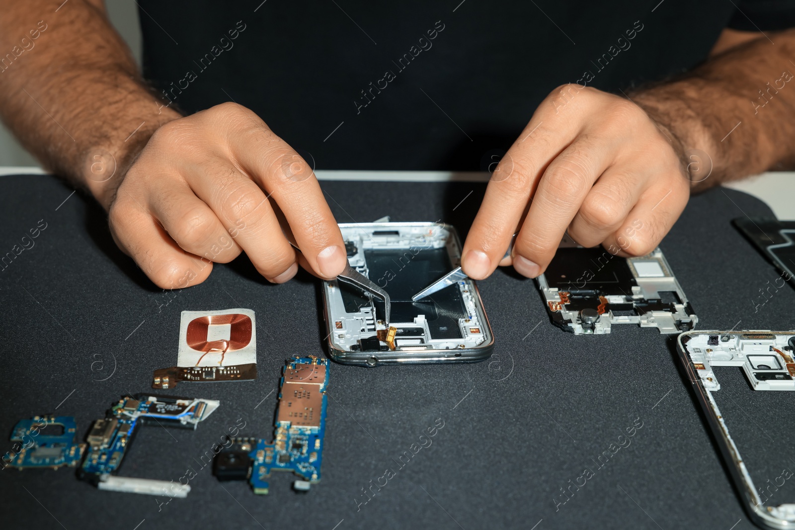 Photo of Technician repairing broken smartphone at table, closeup