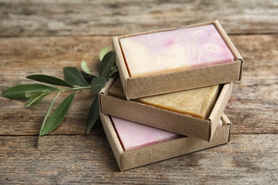 Photo of Packed handmade soap bars and olive twig on table