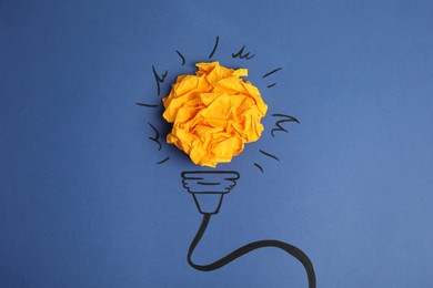 Photo of Composition with crumpled paper ball and drawing of lamp bulb on blue background, top view. Creative concept