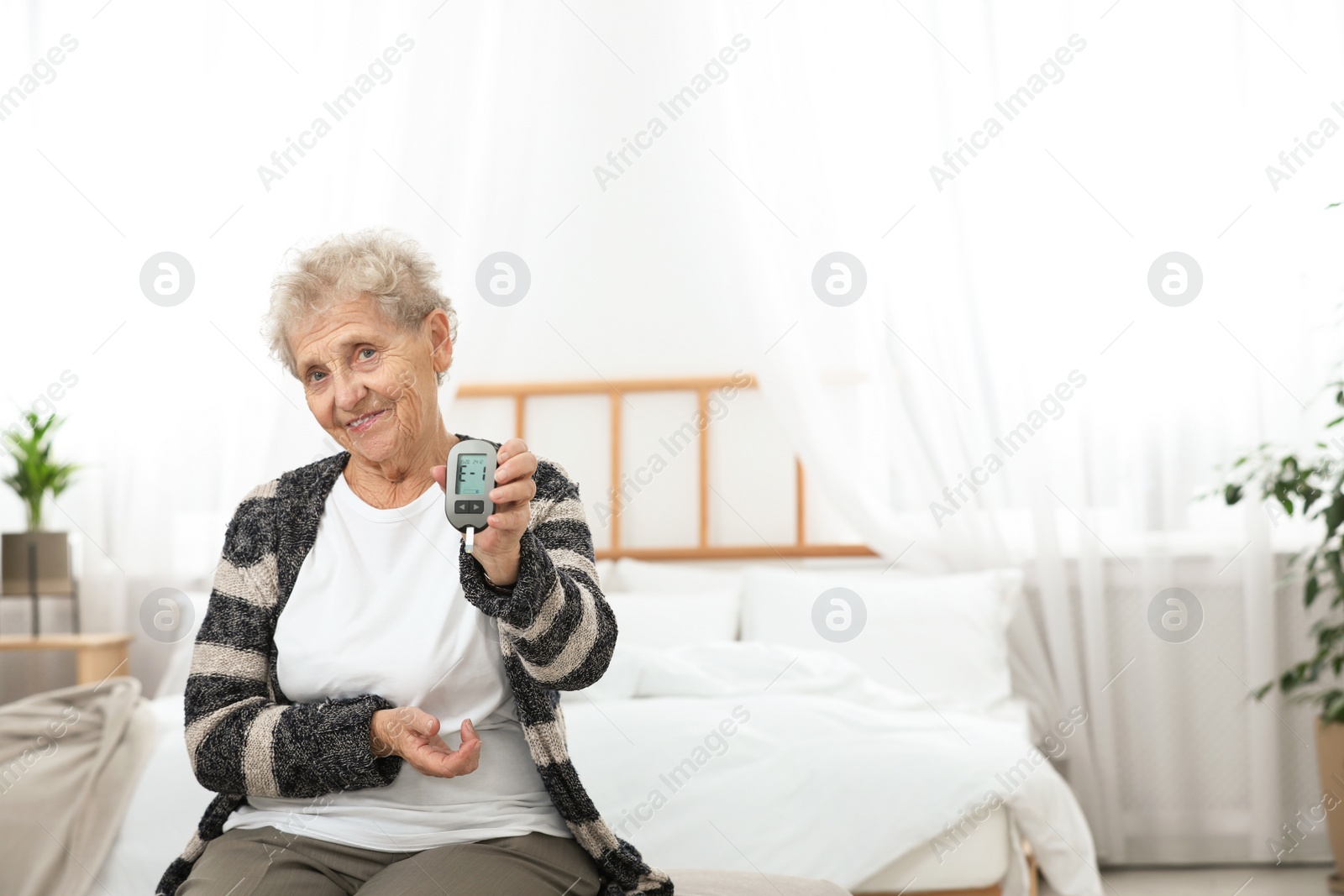 Photo of Senior woman holding digital glucose meter at home. Diabetes control