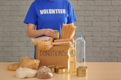 Volunteer collecting food into donation box indoors