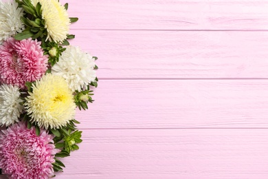 Photo of Beautiful asters and space for text on pink wooden background, flat lay. Autumn flowers