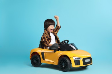 Photo of Little child driving yellow toy car on light blue background