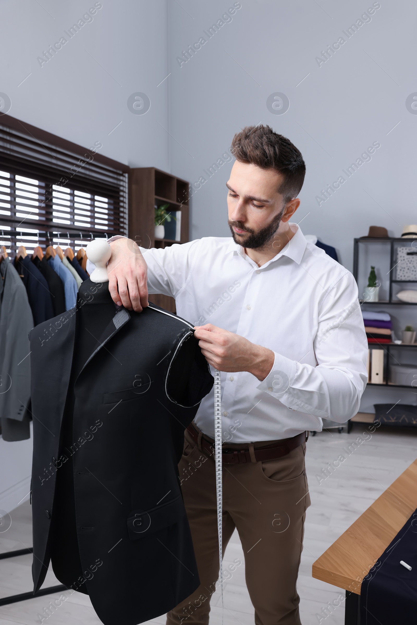 Photo of Dressmaker with measuring tape working in atelier