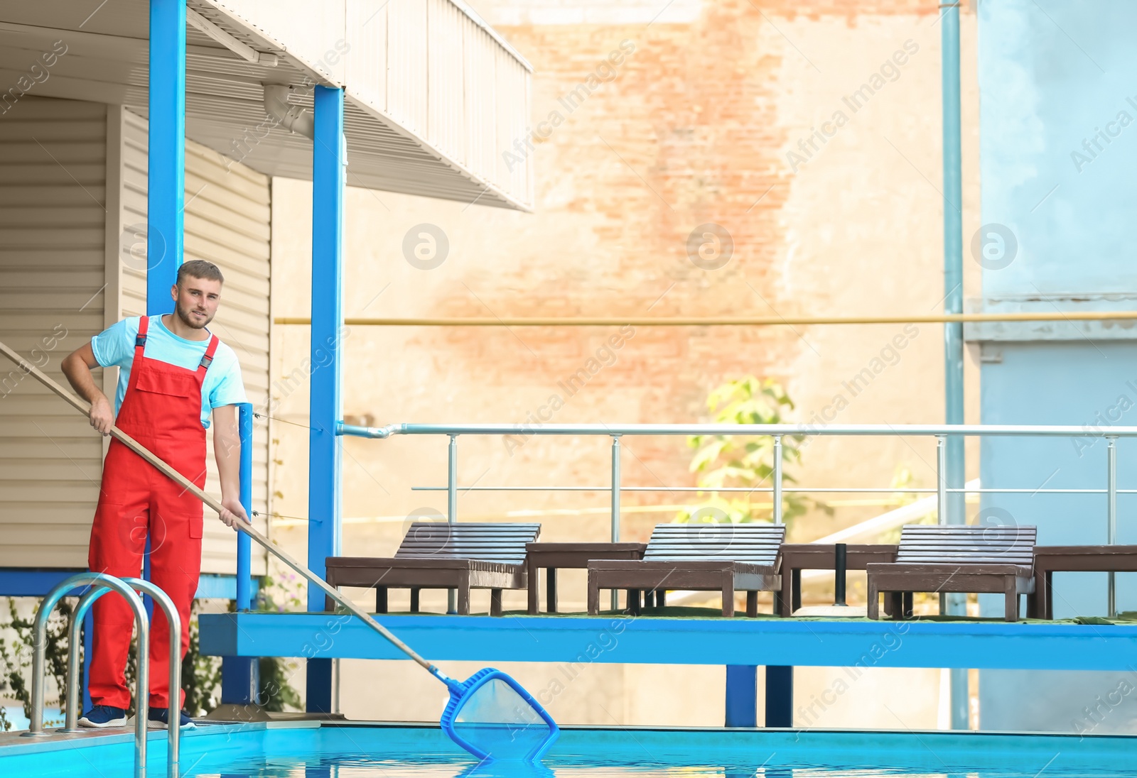 Photo of Male worker cleaning outdoor pool with scoop net