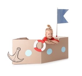 Photo of Cute little girl playing with cardboard ship on white background