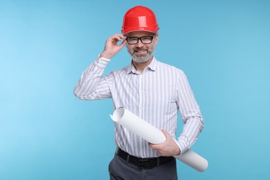 Architect in hard hat holding draft on light blue background