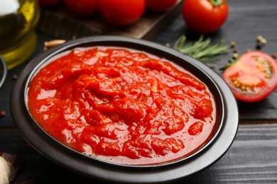 Photo of Homemade tomato sauce in bowl on black table, closeup