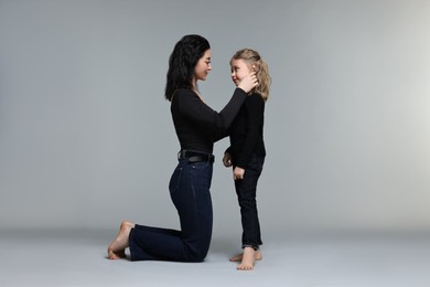 Photo of Beautiful mother with little daughter on grey background