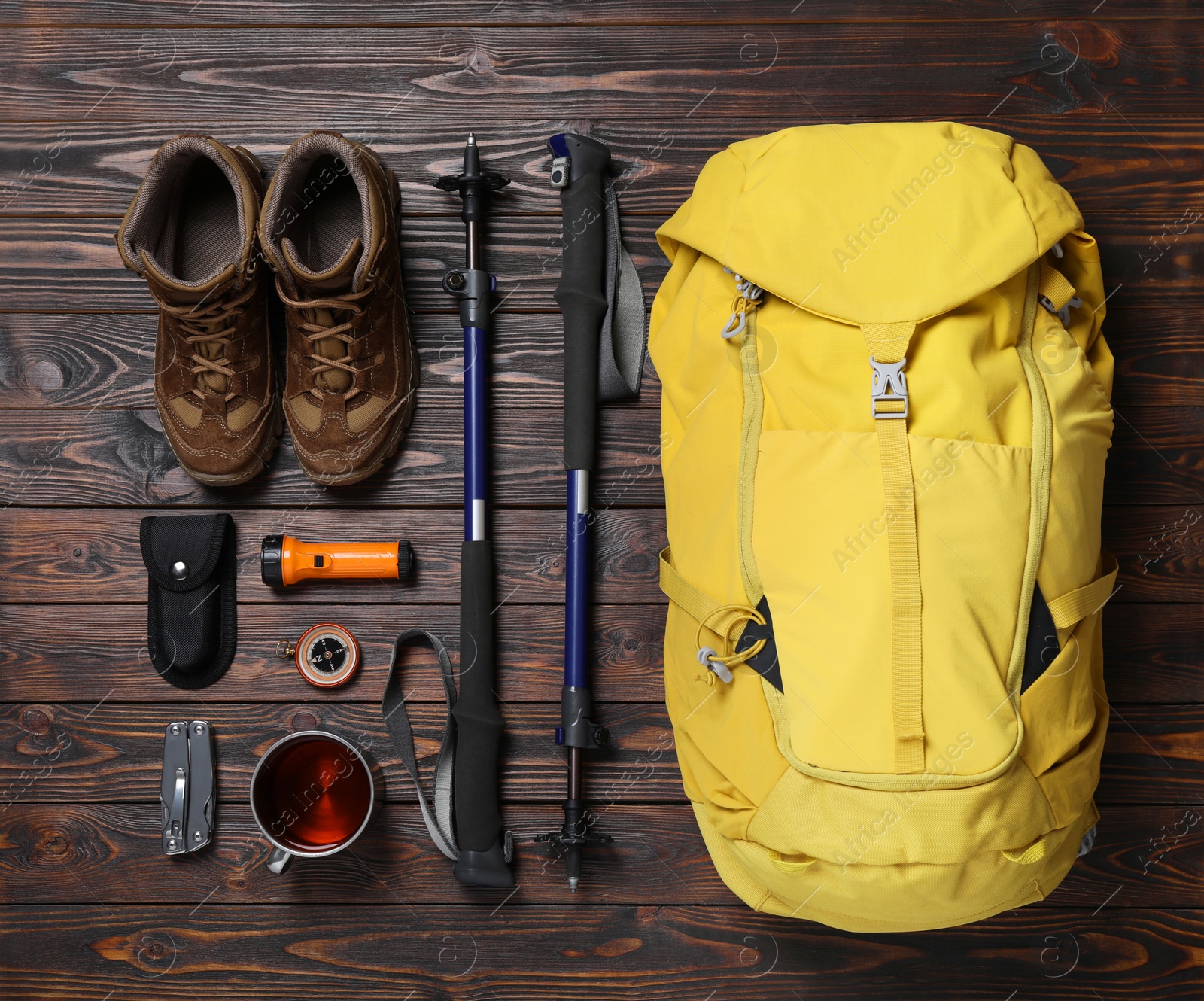 Photo of Flat lay composition with trekking poles and other hiking equipment on wooden background