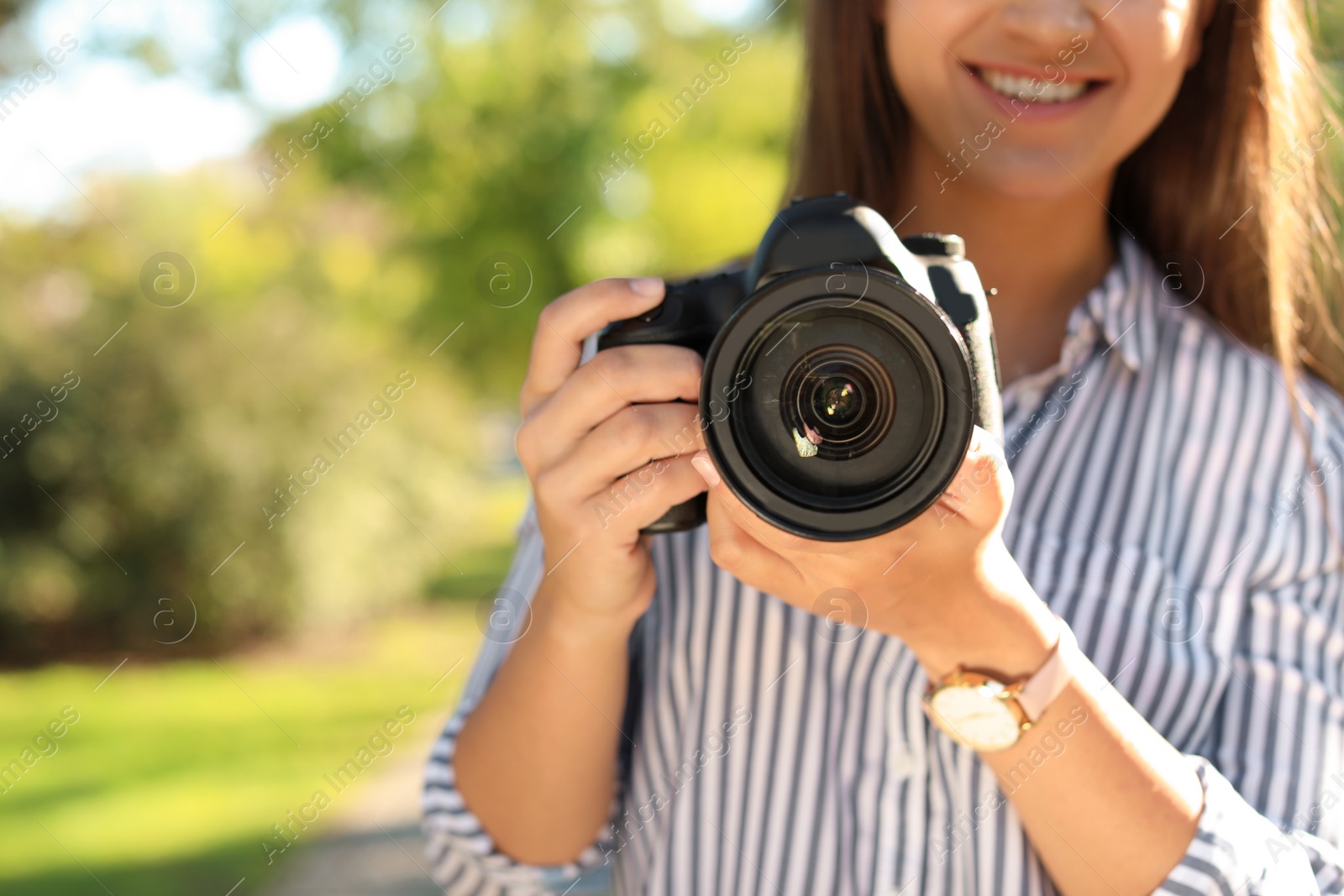 Photo of Young female photographer with professional camera in park, closeup. Space for text