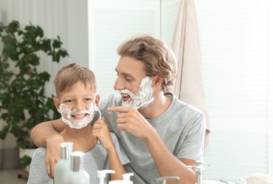 Photo of Father and son shaving together in bathroom