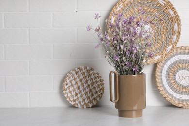 Ceramic vase with dry plants and decor on light table. Space for text