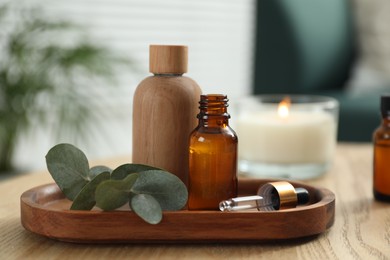Photo of Aromatherapy. Bottles of essential oil and eucalyptus leaves on wooden table