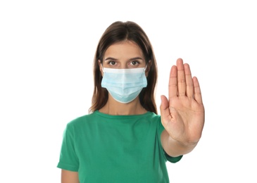 Photo of Woman in protective mask showing stop gesture on white background. Prevent spreading of coronavirus