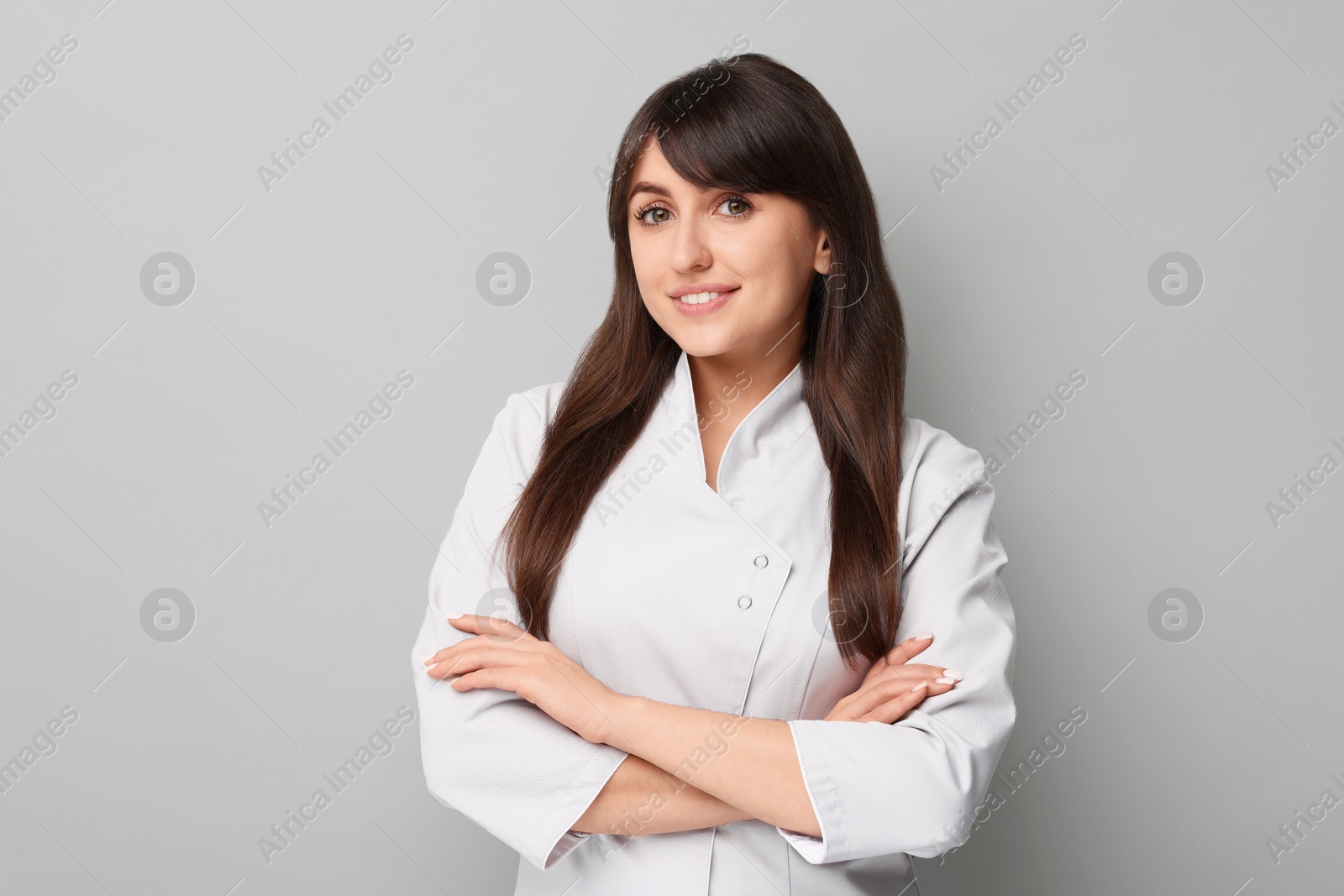 Photo of Cosmetologist in medical uniform on grey background