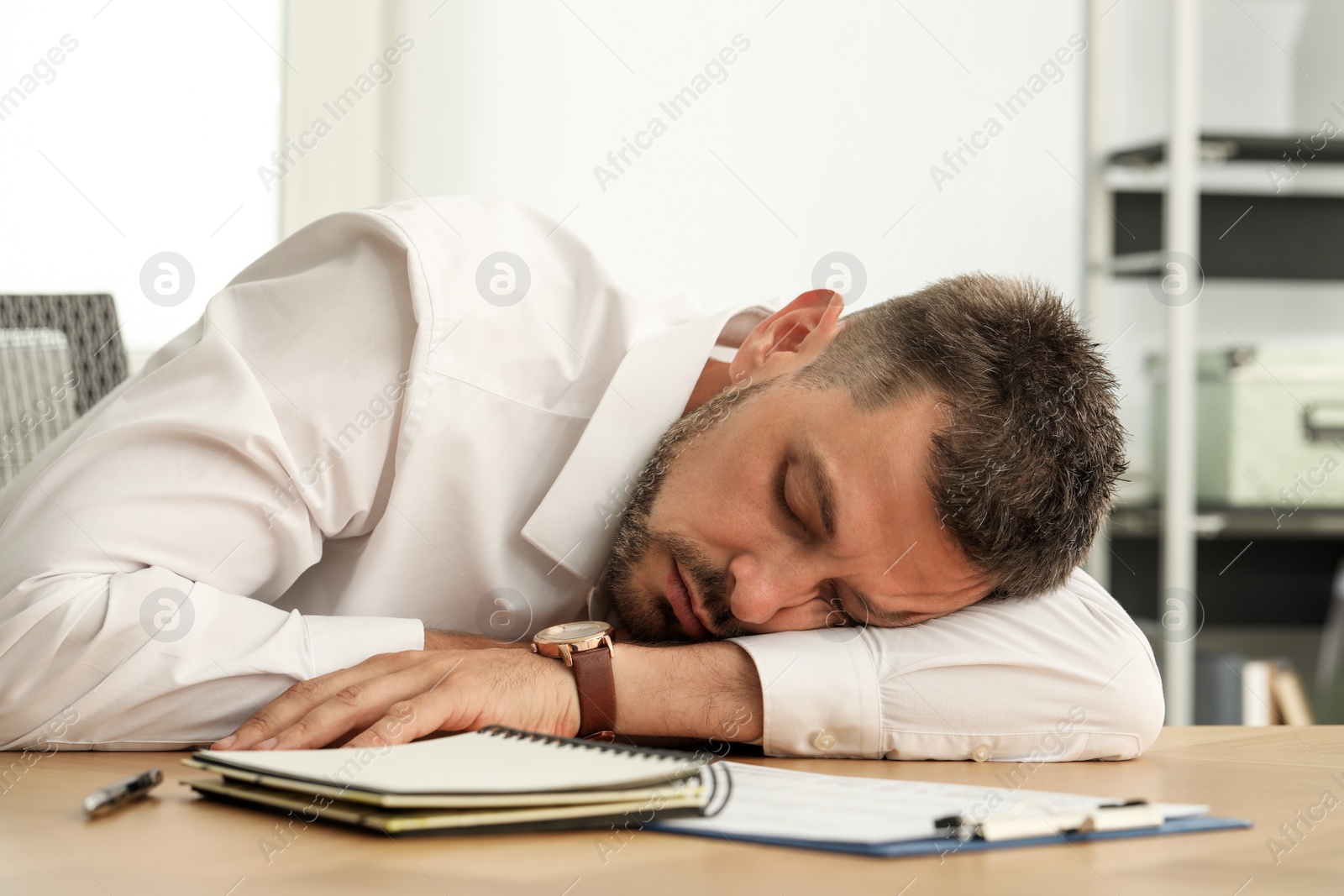 Photo of Tired man sleeping at workplace in office