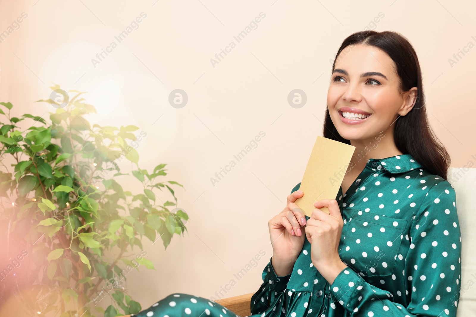 Photo of Happy woman holding greeting card in living room