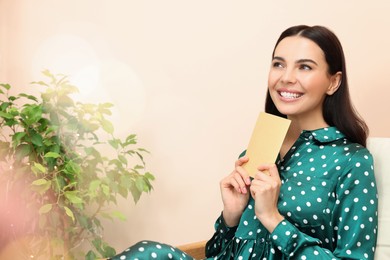 Photo of Happy woman holding greeting card in living room