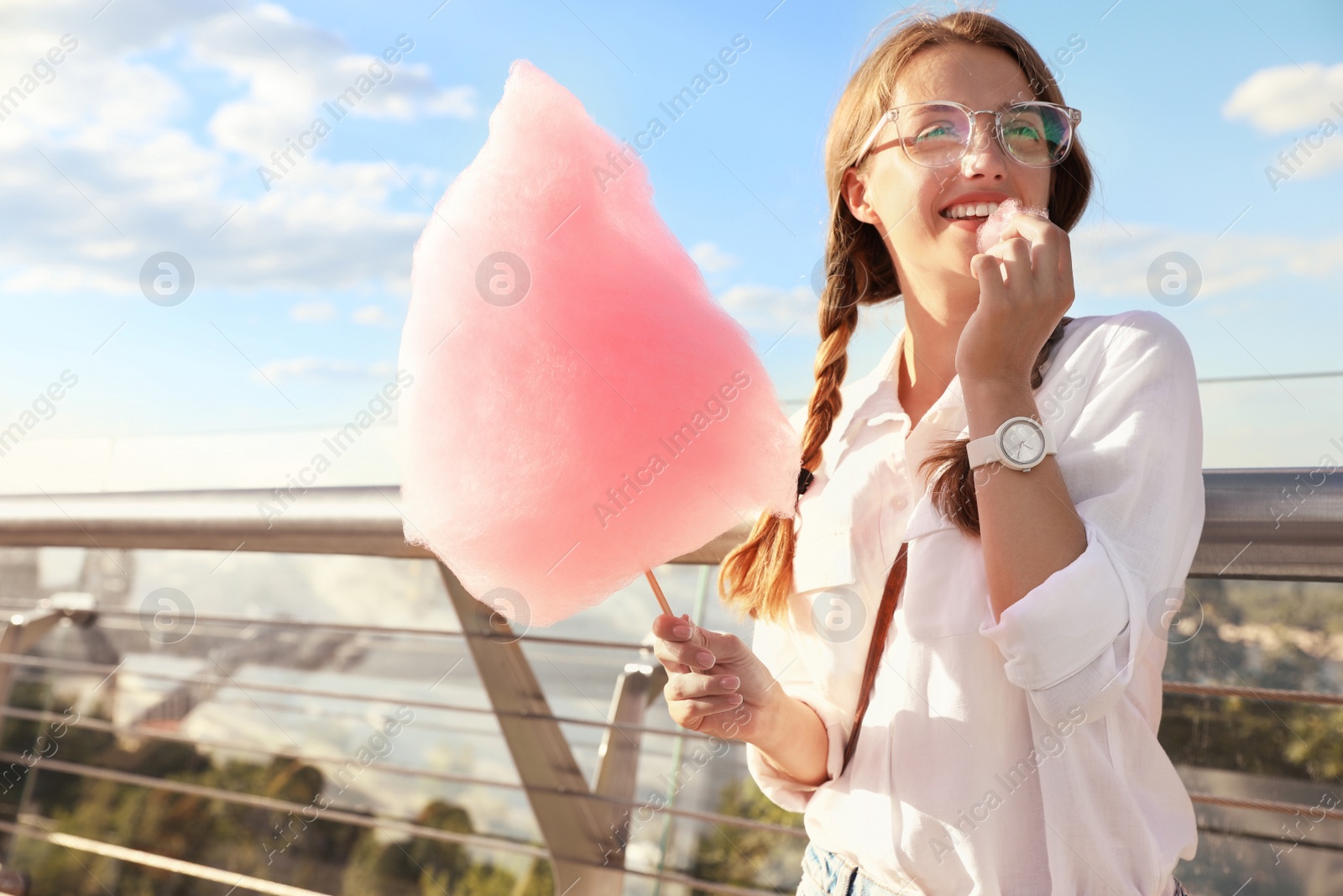Photo of Young woman with cotton candy outdoors on sunny day