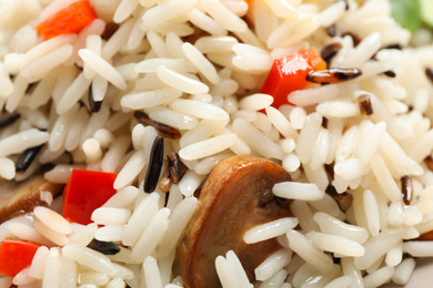 Photo of Delicious rice pilaf with bell peppers and mushrooms as background, closeup