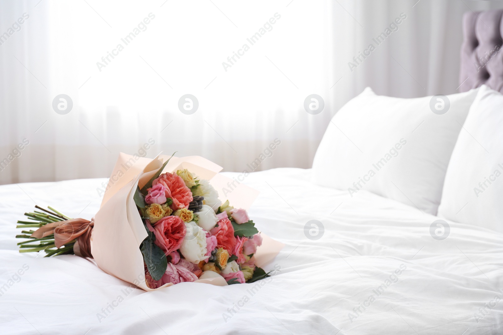 Photo of Beautiful flower bouquet on bed in light room. Space for text