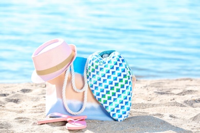 Bag, towel, hat and flip flops on sand near sea. Beach object