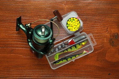Fishing tackle. Spinning reel, lures and bait on wooden table, flat lay
