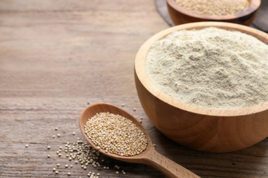 Quinoa flour in bowl and spoon with seeds on wooden table