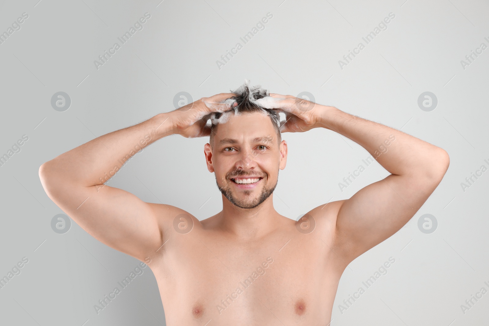 Photo of Handsome man washing hair on white background