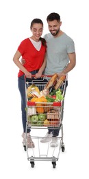 Photo of Happy couple with shopping cart full of groceries on white background
