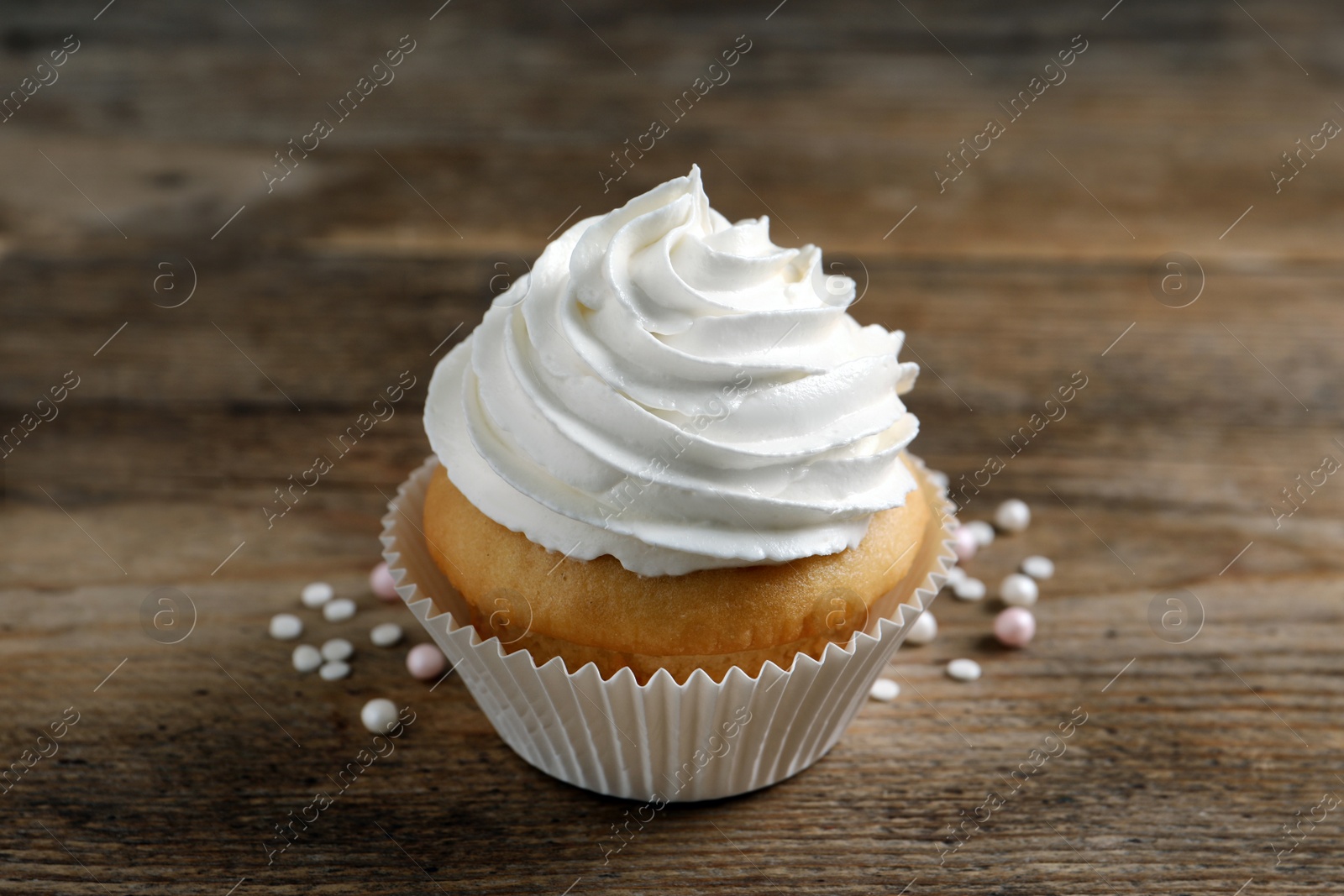 Photo of Delicious cupcake with cream on wooden table, closeup