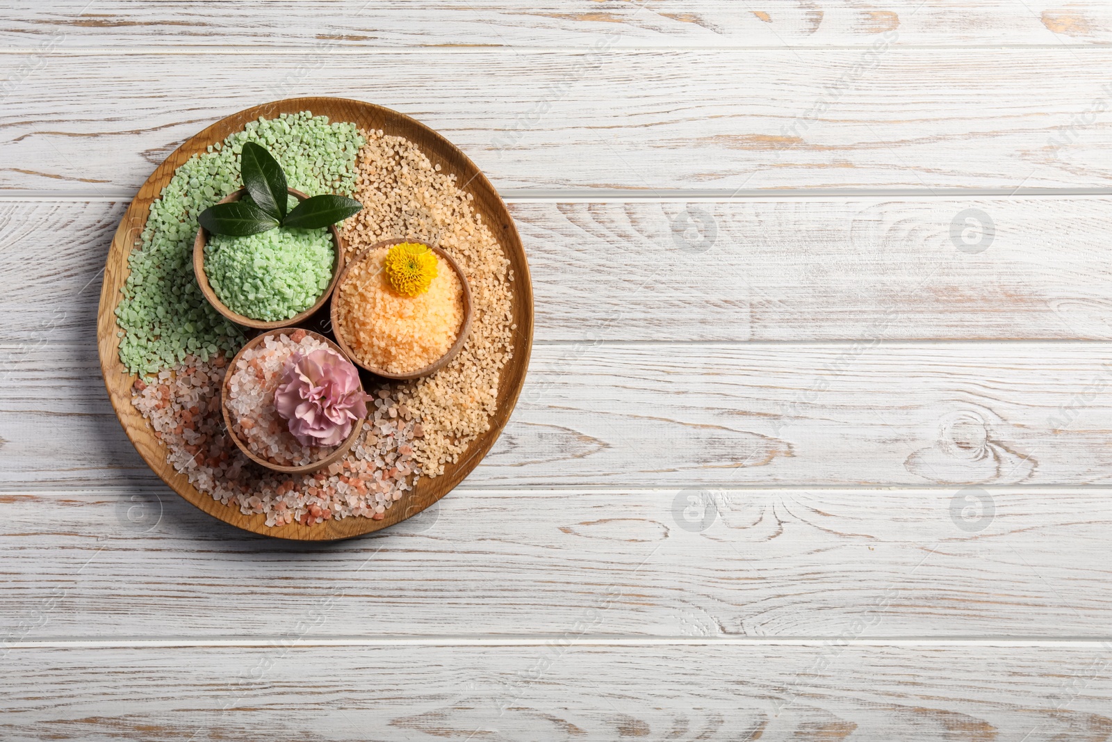 Photo of Different types of aromatic sea salt on white wooden table, top view. Space for text