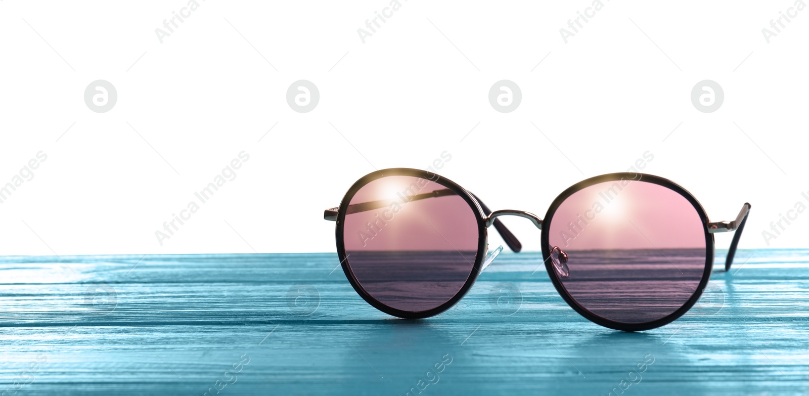 Photo of Stylish sunglasses on light blue wooden table against white background. Space for text