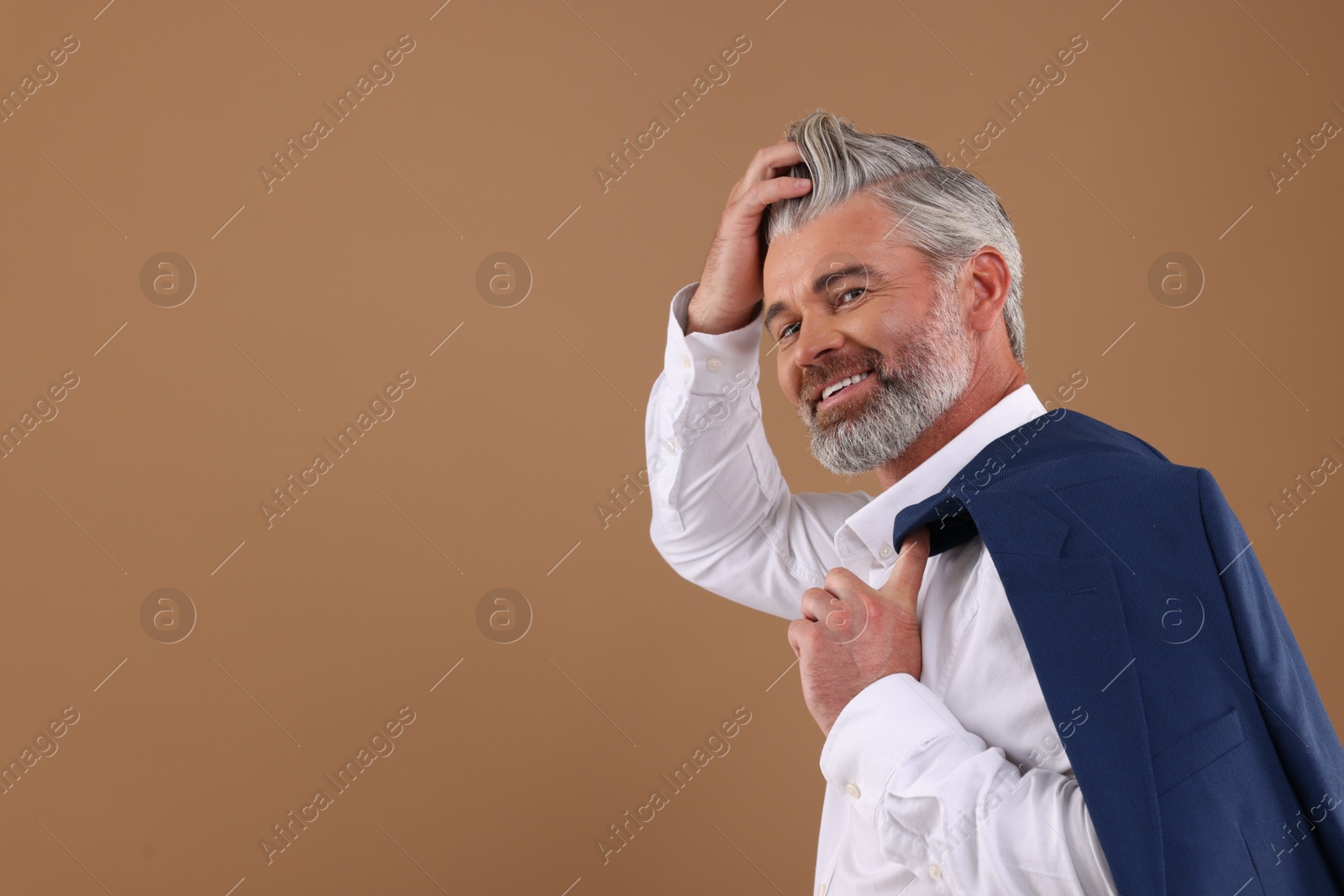 Photo of Portrait of smiling man with beautiful hairstyle on light brown background. Space for text