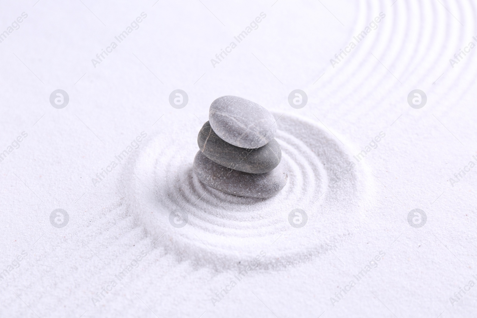 Photo of Zen garden stones on white sand with pattern