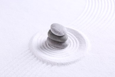 Photo of Zen garden stones on white sand with pattern