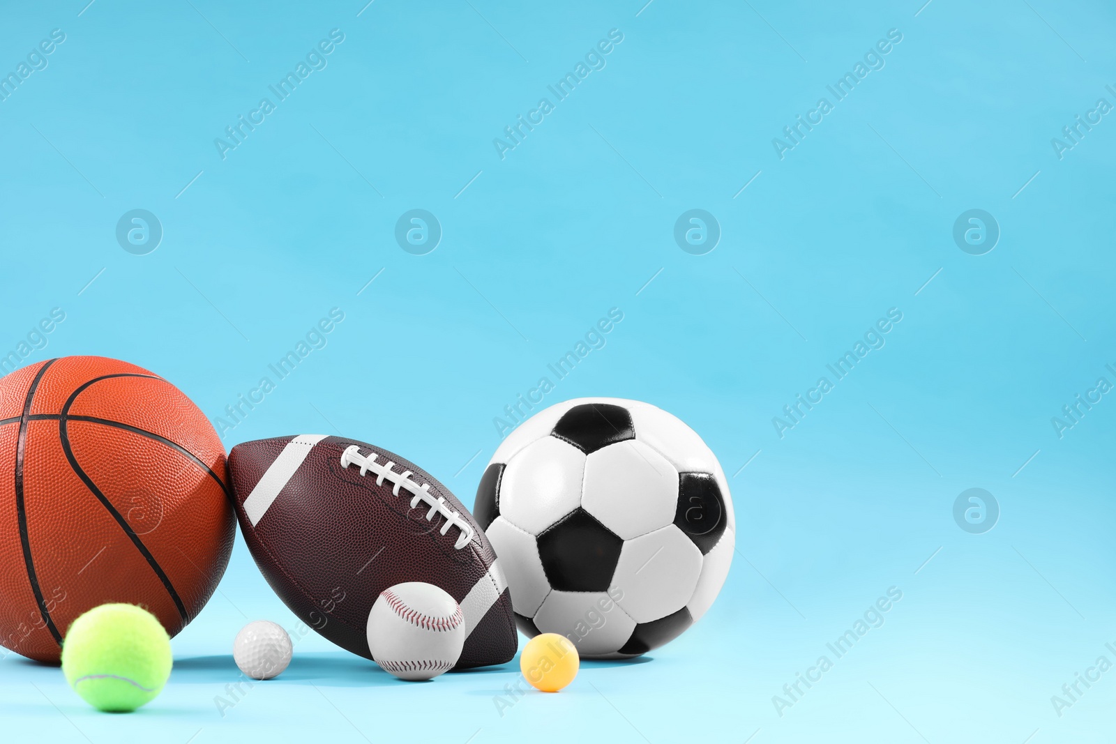 Photo of Many different sports balls on light blue background, space for text