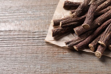 Dried sticks of liquorice root on wooden table, space for text