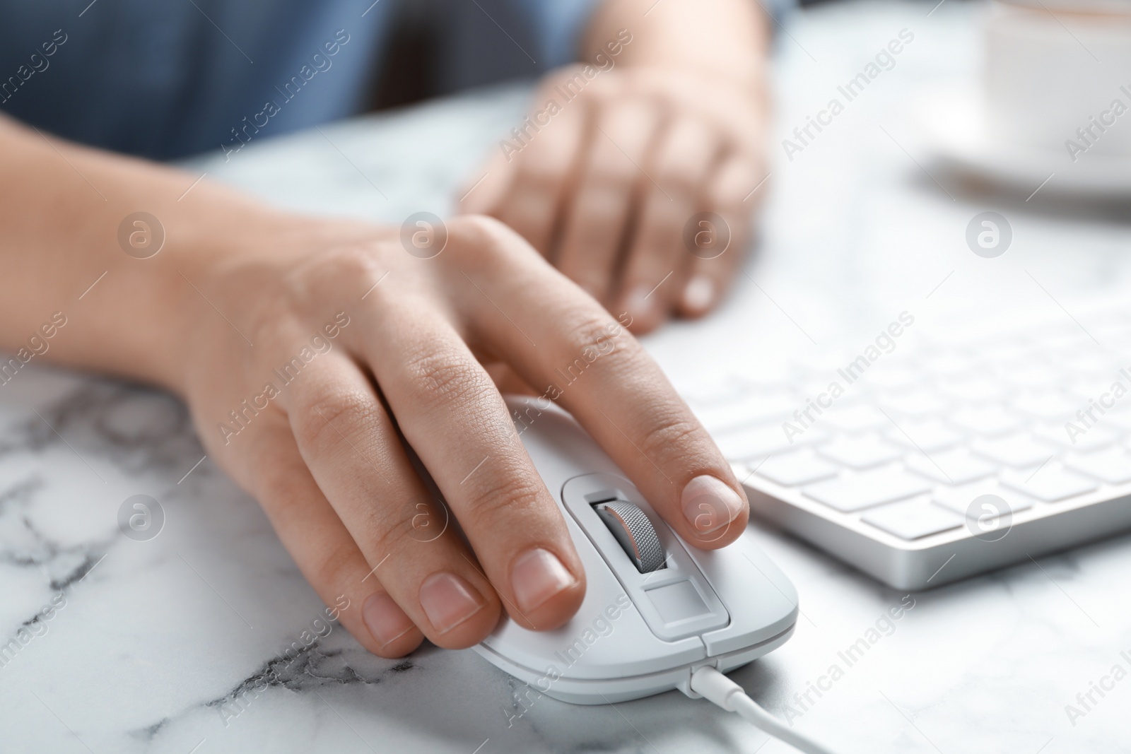 Photo of Woman using wired computer mouse at marble table, closeup