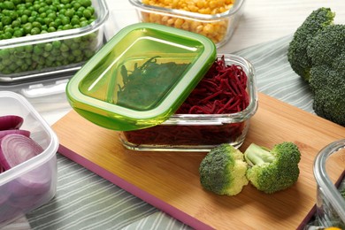 Photo of Containers with cut beetroot and fresh products on table. Food storage