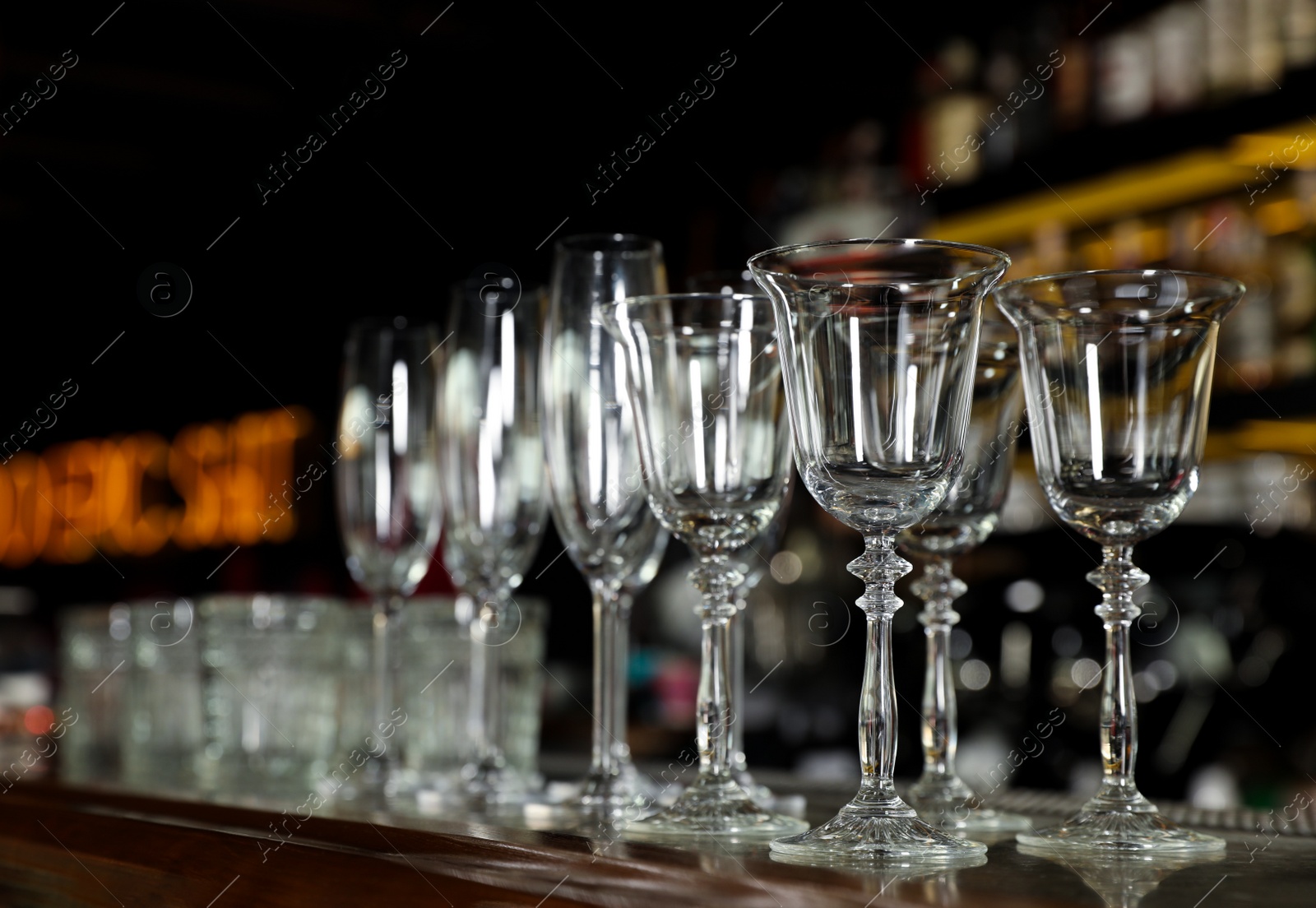 Photo of Different empty clean glasses on counter in bar