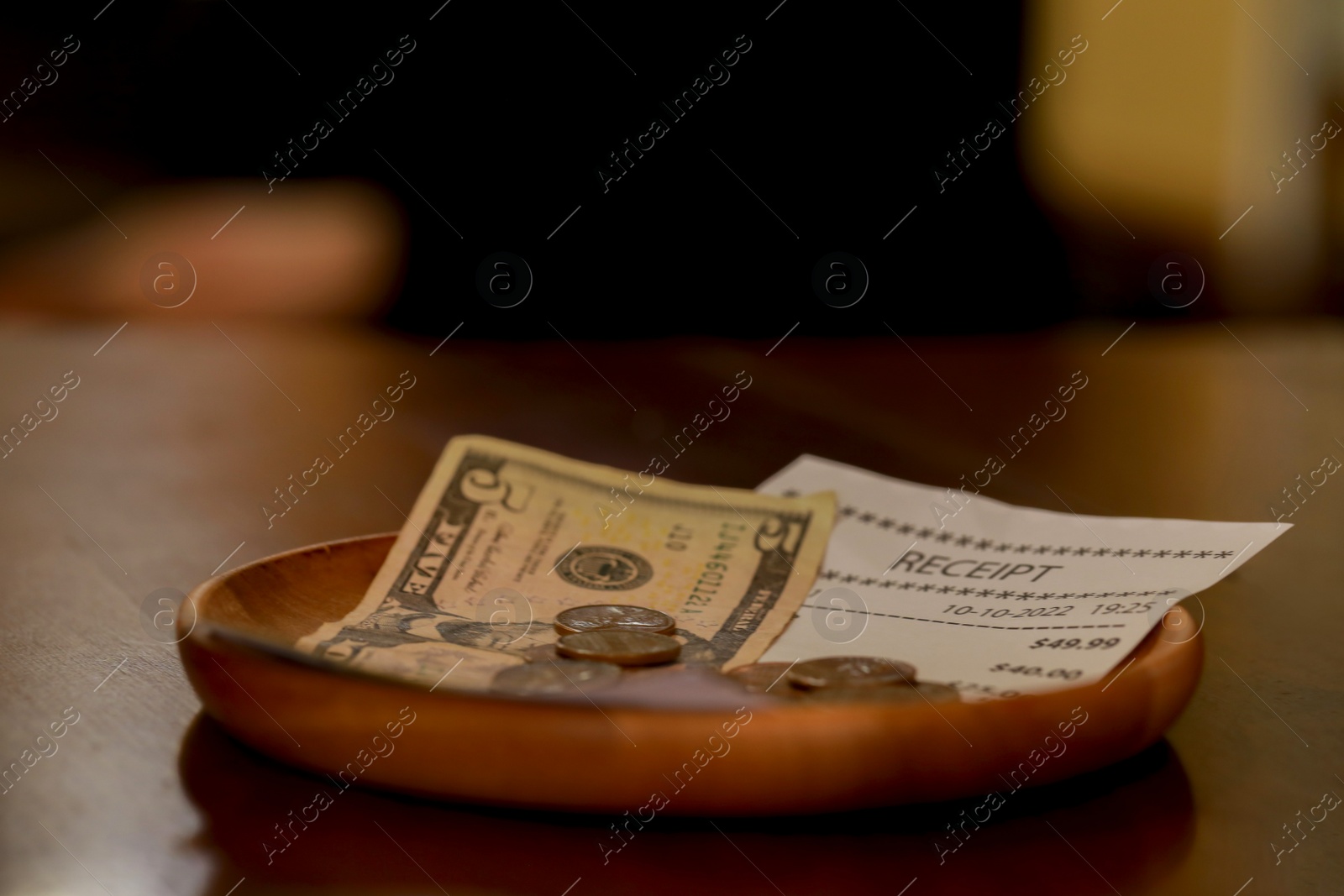Photo of Tips and receipt on wooden table, closeup