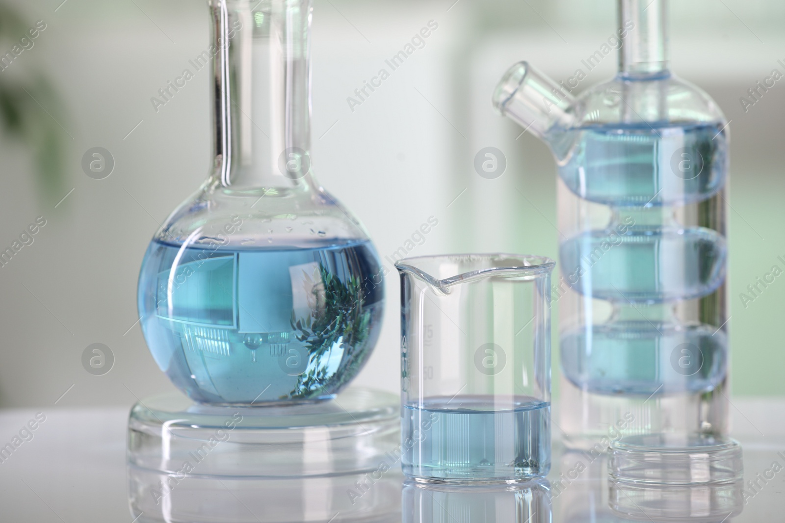 Photo of Laboratory analysis. Different glassware with liquid on white table against blurred background, closeup